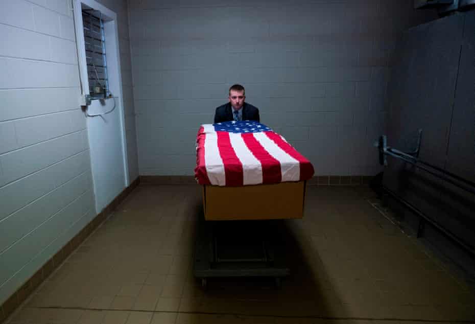 Brandon Cochran, a crematory operator, pushes a cremation box draped in a US national flag, containing the body of a veteran who died of coronavirus.