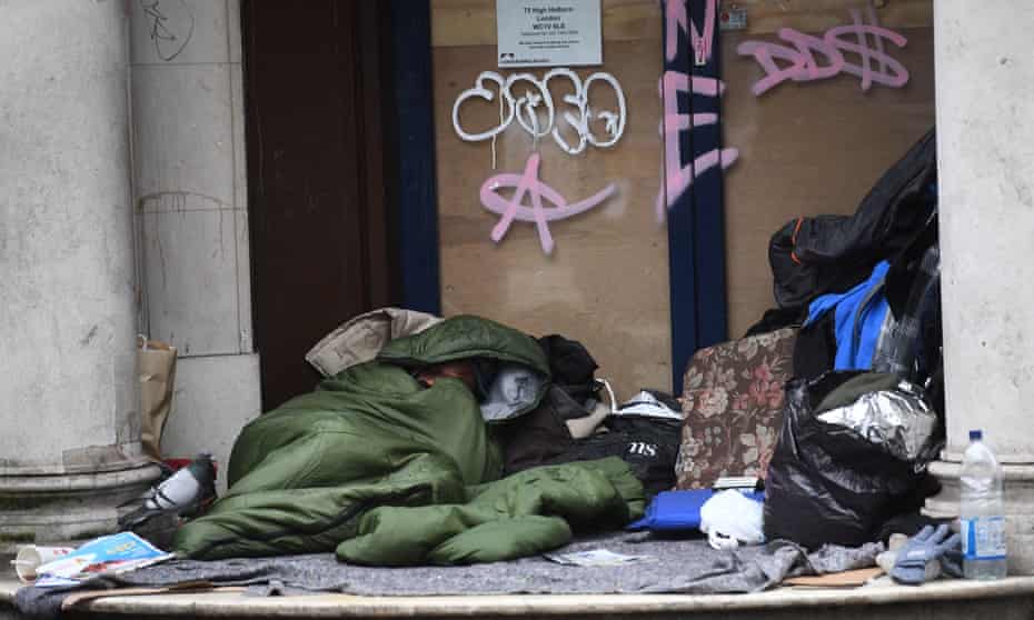 A homeless man sleeps in the doorway of a closed branch of the Leeds building society in Holborn, London