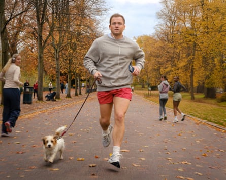 man running with dog in park during autumn