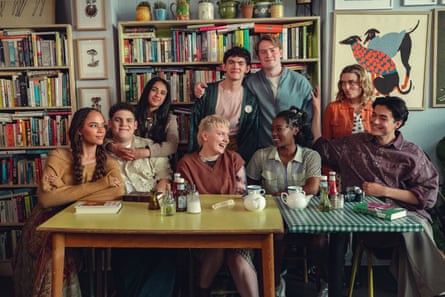 A group of young friends sit and stand infront of a crammed bookcase.