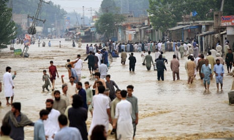 People wade through a flooded area after heavy rains in Charsadda district, Khyber Pakhtunkhwa province.