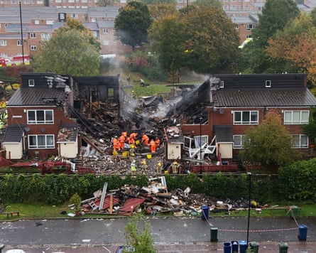 Emergency workers at the scene of the explosion surrounded by the rubble of destroyed houses