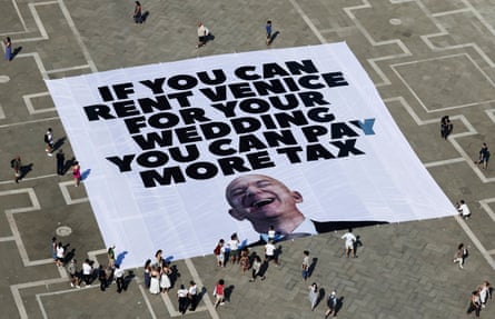 A large banner that says ‘If you can rent Venice for your wedding you can pay more tax’ above a picture of Bezos laughing