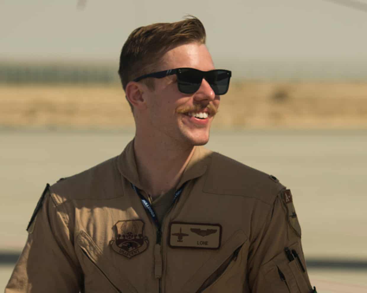 Jacob Wulfson smiling in sunglasses and a tan flight suit outdoors