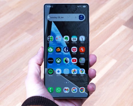 Samsung Galaxy S25 Ultra review showing the homescreen held in a hand above a table.