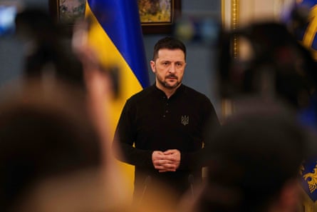 Volodymyr Zelenskyy standing in front of a Ukrainian flag