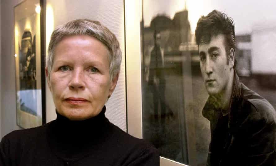 Astrid Kirchherr posing next to one of her images of John Lennon.