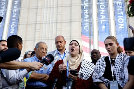 A woman speaks outside a building while surrounded by people