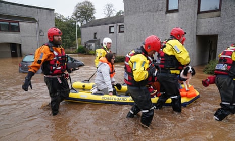 Members of the emergency services help to move a woman and a dog on a boat in Brechin.