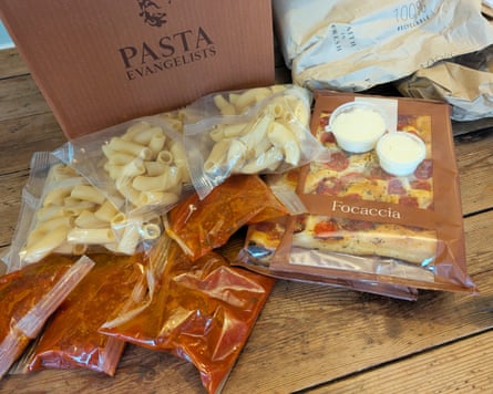 The elements of a Pasta Evangelist box are displayed including pasta portions, sauces and breads all individually wrapped in plastic.