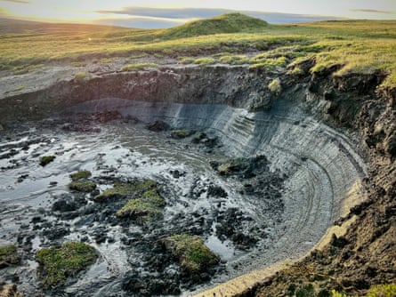 A crater of black earth surrounded by green grass