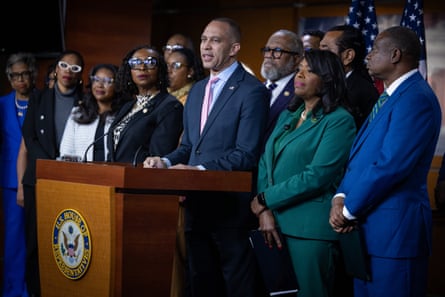 a man speaking at a podium surrounded by other people