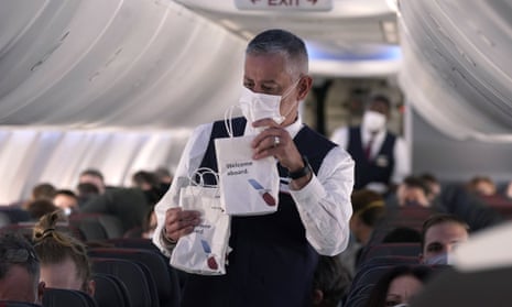 An American Airlines flight attendant wearing mask handing out snacks
