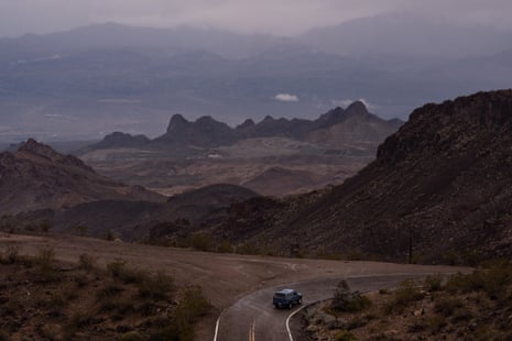 A car on a bend in the highway with mountains in the background