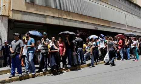 People queue to buy basic food items outside a supermarket in Caracas.