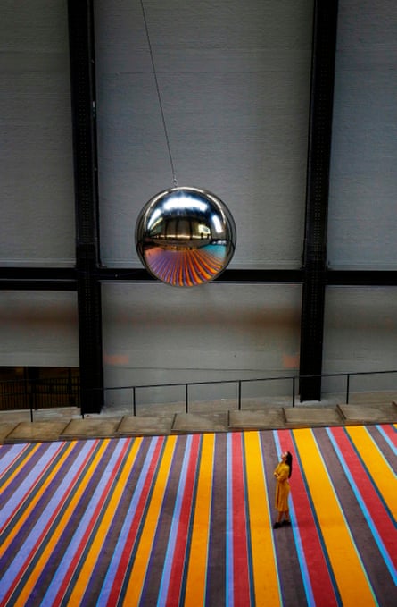A woman looks up at a giant pendulum