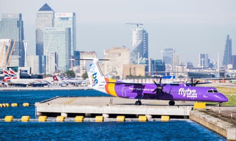 Plane at London City airport with Thames and Canary Wharf in background.