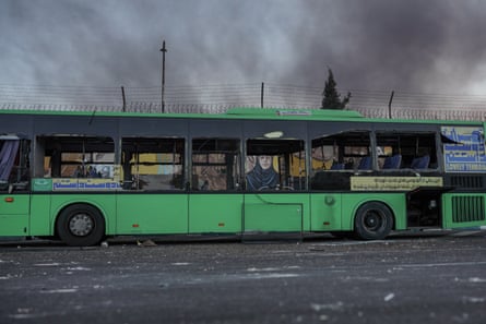 Green bus with its windows blown out. It has a large sticker saying 'Lovely Tehran' at one end