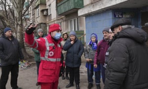 People talk with a Red Cross worker next to an apartment building in Mariupol, Ukraine.