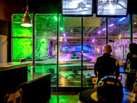 Two people watching a go-kart drive around a track in a bunker in Helsinki.