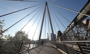 A man walking along the Golden Jubilee Bridge in London.