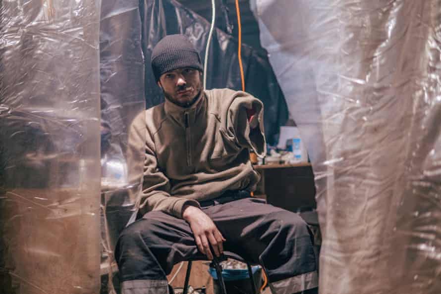 An injured Ukrainian work subordinate sits successful the dimly-lit, makeshift hospital.