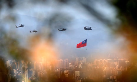 Military helicopters, one trailing a Taiwan flag, rehearse for Taiwanese national day celebrations.
