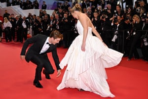 Robert Pattinson and Jennifer Lawrence smile as Pattinson bends down to check Lawrence's dress