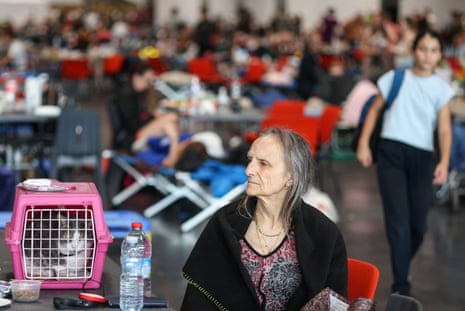 A woman sits in the Bordeaux-Lac Exhibition Centre, which has been turned into a shelter for people displaced by the wildfire.