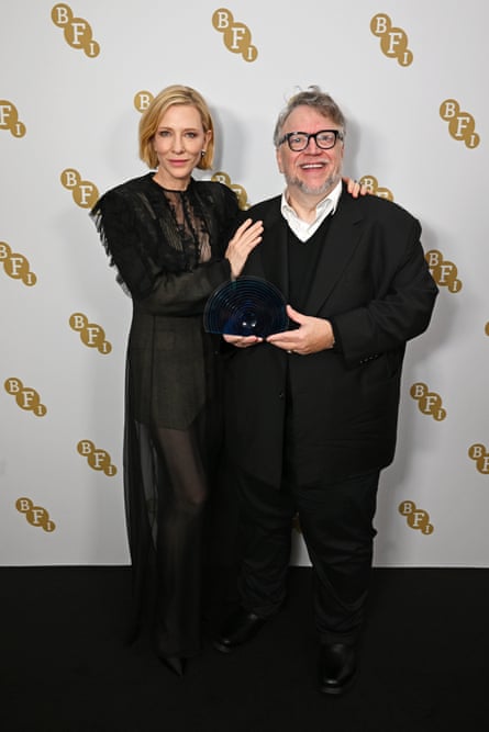 Blanchett and del Toro with an award, both dressed in black
