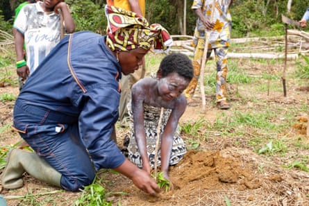 A woman and a child put a plant in the ground