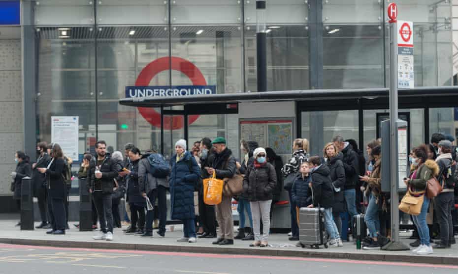 bus passengers queue outside a tube station