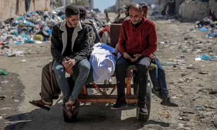Men sit around a shrouded body on a cart pulled by a donkey