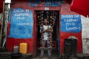 Fabrice, 20, poses in front of his hairdressing salon in Goma, Democratic Republic of Congo
