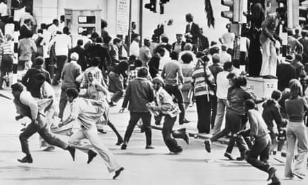 Demonstran anti-apartheid melarikan diri dari kejaran polisi selama kerusuhan rasial, di Cape Town, selama bentrokan tahun 1976.
