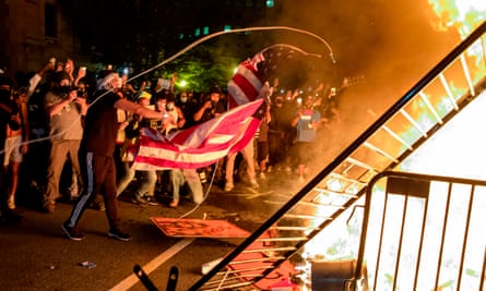 Protesters throw a US flag into a fire during a demonstration outside the White House.