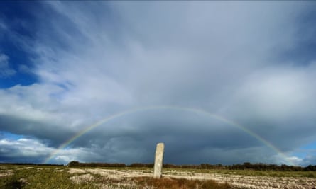 A still from A Year in a Field shows a rainbow framing the stone.