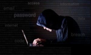 A hacker in a hoodie on a laptop