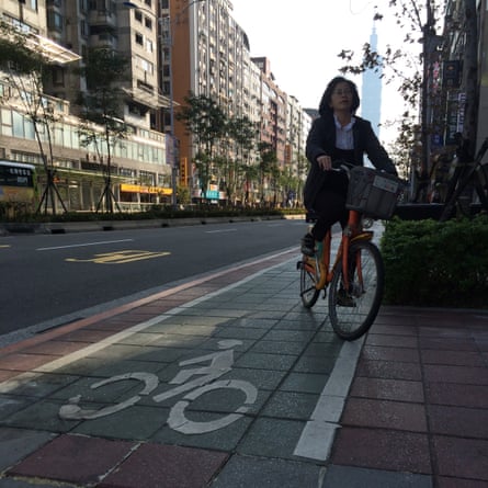 Cycling on a segregated pavement bike lane, with Taipei 101 tower in the background.