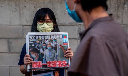 A woman holding a copy of the Apple Daily newspaper.