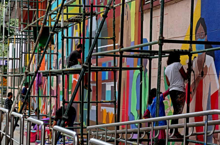 Members of the Aravani collective work on graffiti depicting the history of coronavirus in Bangalore