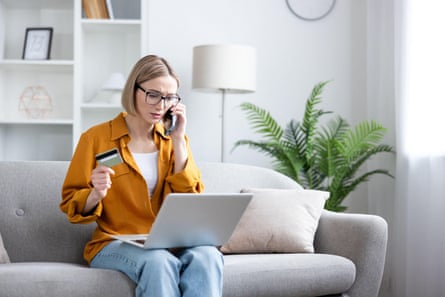 Woman holding a credit card and talking on a smartphone during a stressful call