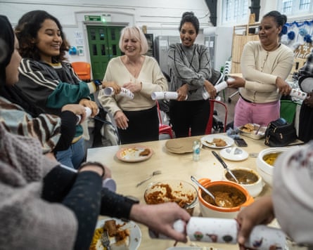 People stand around the table holding Christmas crackers