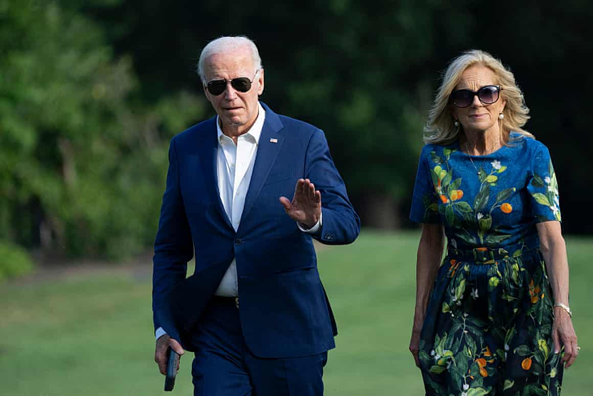 Joe Biden waves as he walks alongside Jill Biden