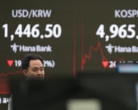 A dealer walks past near screens showing the Korea composite stock price index in Seoul, South Korea