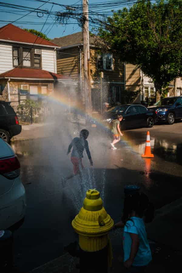 A group of children play in a stream of water from an uncapped fire hydrant in Corona, Queens.