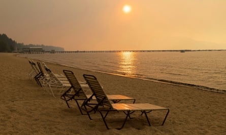 Empty chairs stand on the beach with the sky obscured by the smoke of the Caldor fire, in South Lake Tahoe, California, in August.