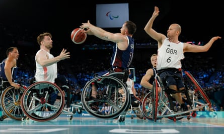 Team USA and Paralympics GB basketball players tussle for a loose ball on court.