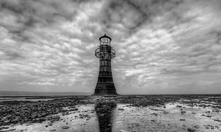 haunted caves uk Lighthouse at Whiteford with dramatic sky black and white image