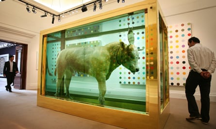 A whole pickled calf in a golden-lined glass case, set in the middle of a room in a gallery
